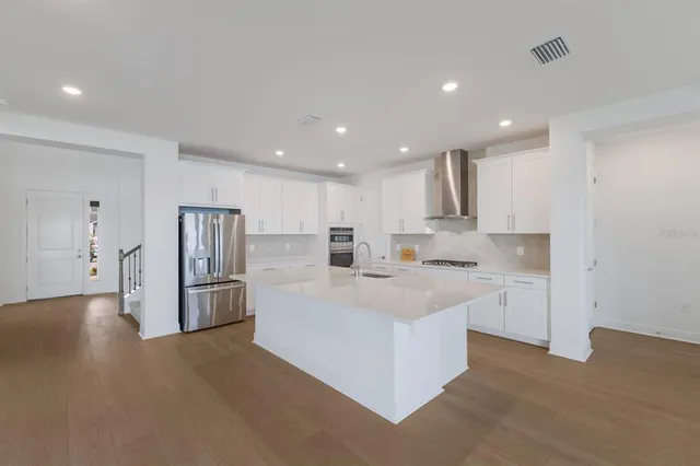 a large white kitchen with a sink and refrigerator