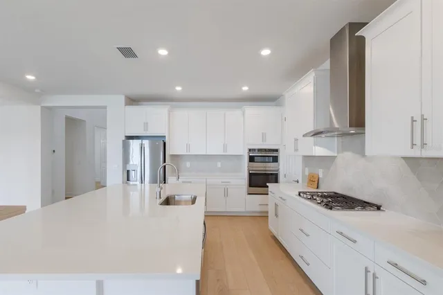a large white kitchen with stainless steel appliances