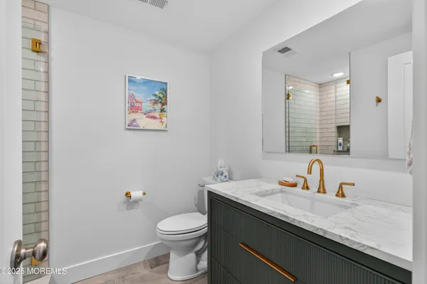 a bathroom with a granite countertop sink mirror vanity and toilet