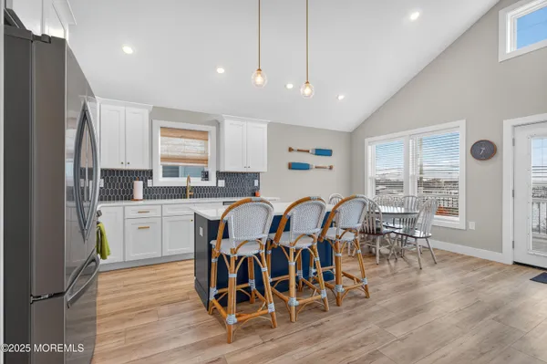 a kitchen with stainless steel appliances granite countertop a dining table chairs stove refrigerator and cabinets