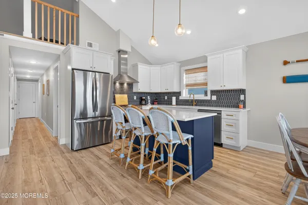 a kitchen with stainless steel appliances a refrigerator a stove a sink dishwasher a dining table and chairs with wooden floor