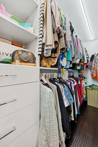 a view of walk in closet with clothes and shoes