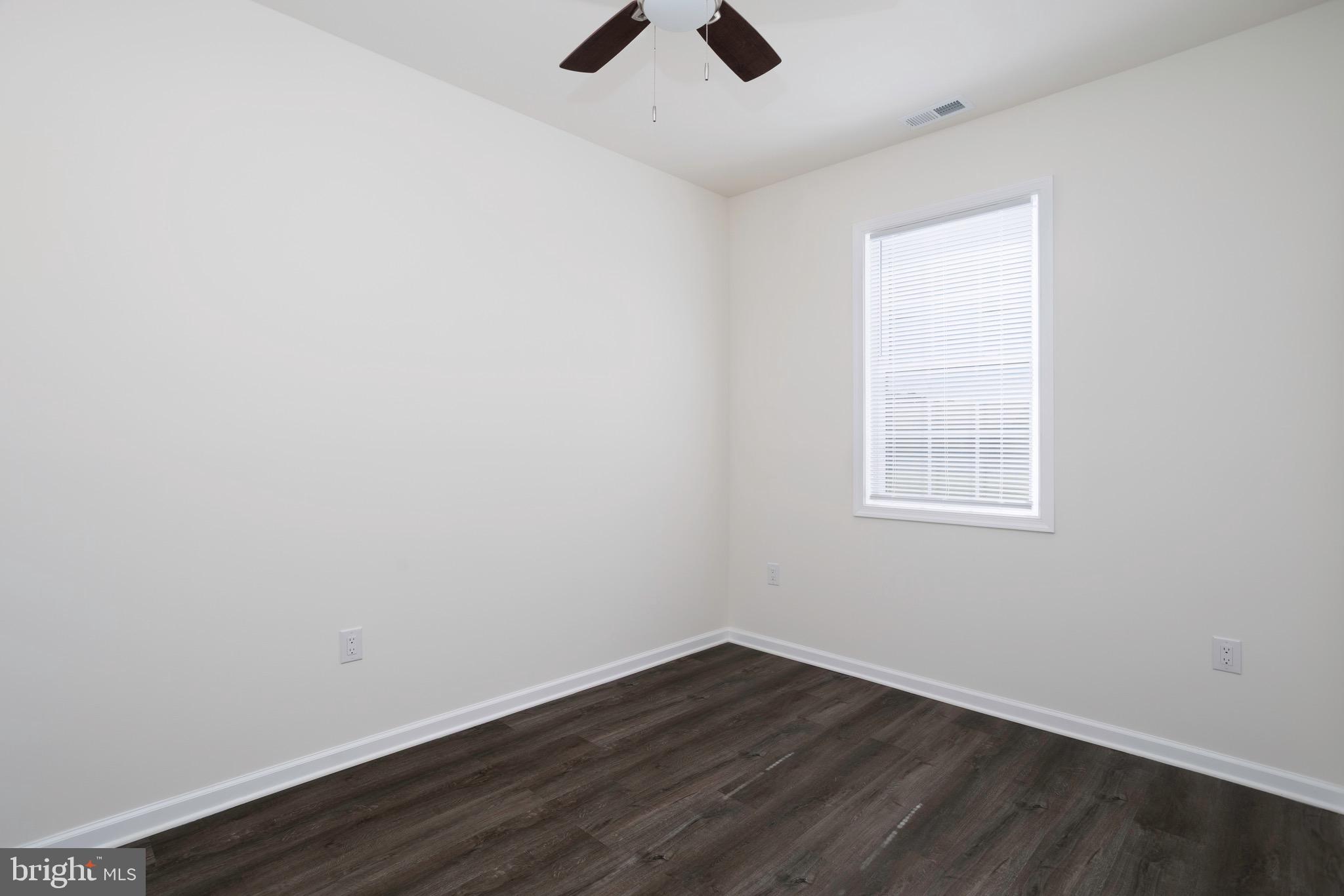 453 Willis Street Cambridge, MD 21613 - Photo 17 of 18 an empty room with wooden floor chandelier fan and windows