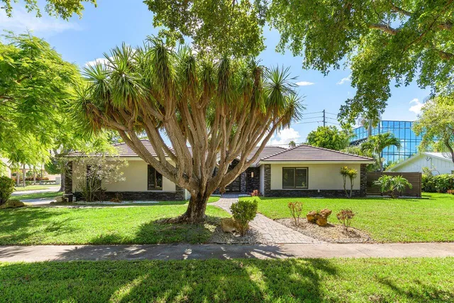 a front view of a house with a garden and tree