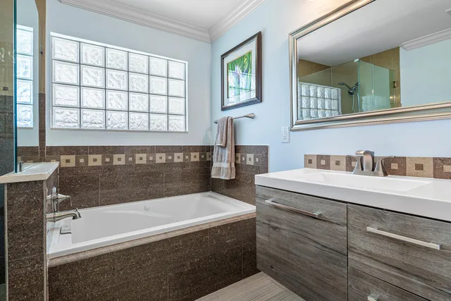a bathroom with a double vanity sink mirror and bathtub