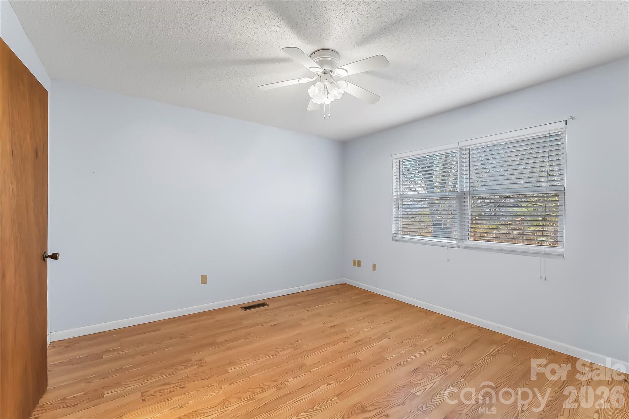 350 Sandy Bottom Road Marshall, NC 28753 - Photo 11 of 40 an empty room with a chandelier fan and windows