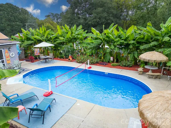 a view of a swimming pool with lawn chairs under an umbrella