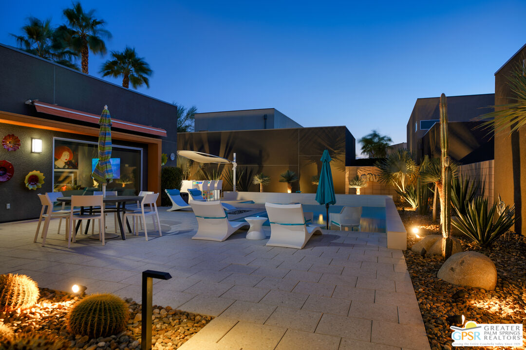 1069 Dane Drive Palm Springs, CA 92262 - Photo 15 of 51 a view of a patio with dining table and chairs under an umbrella with a fire pit