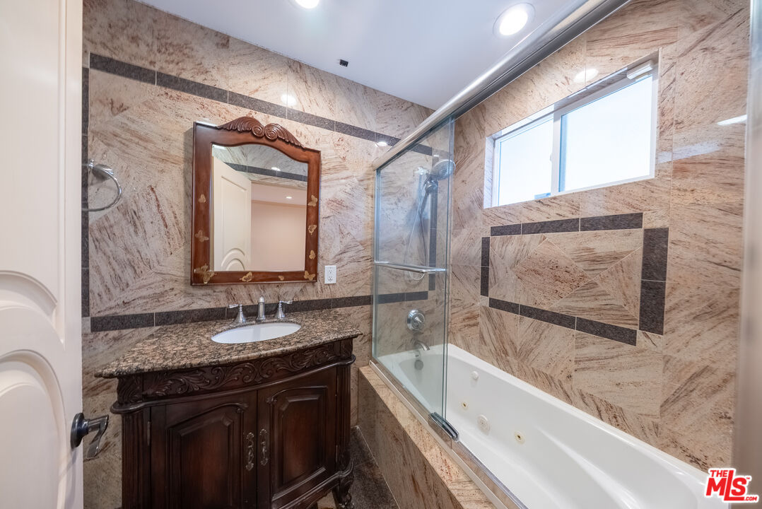 13847 Gilmore Street Van Nuys, CA 91401 - Photo 14 of 43 a bathroom with a granite countertop sink a mirror and a bathtub