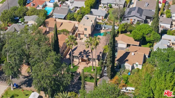 an aerial view of residential houses with outdoor space and trees