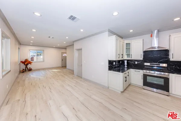 a large white kitchen with stainless steel appliances granite countertop a stove a sink and dishwasher