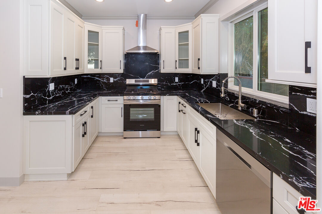 13847 Gilmore Street Van Nuys, CA 91401 - Photo 36 of 43 a large white kitchen with stainless steel appliances granite countertop a stove a sink and dishwasher