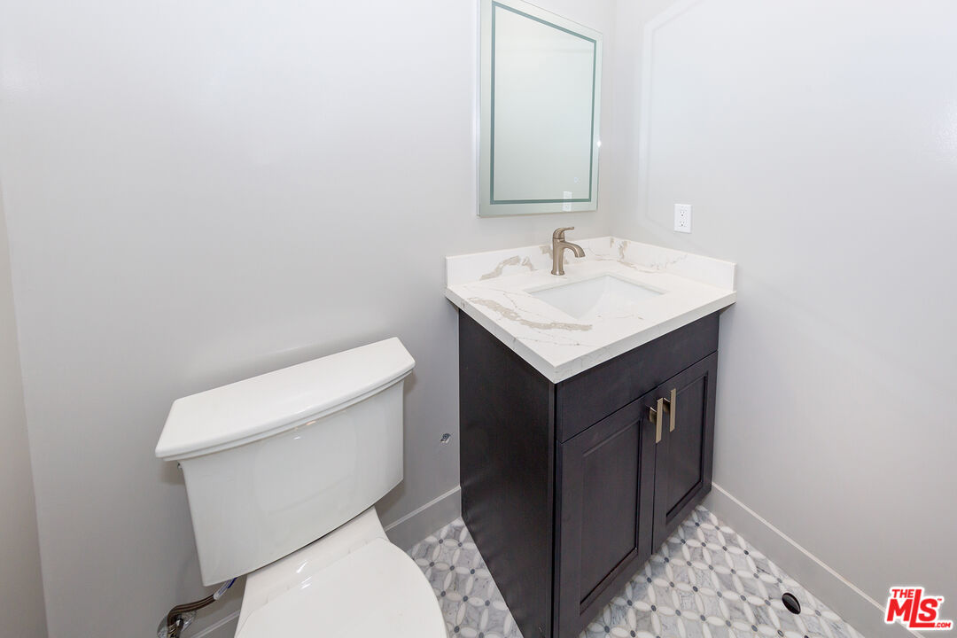 13847 Gilmore Street Van Nuys, CA 91401 - Photo 37 of 43 a bathroom with a sink a toilet and a mirror