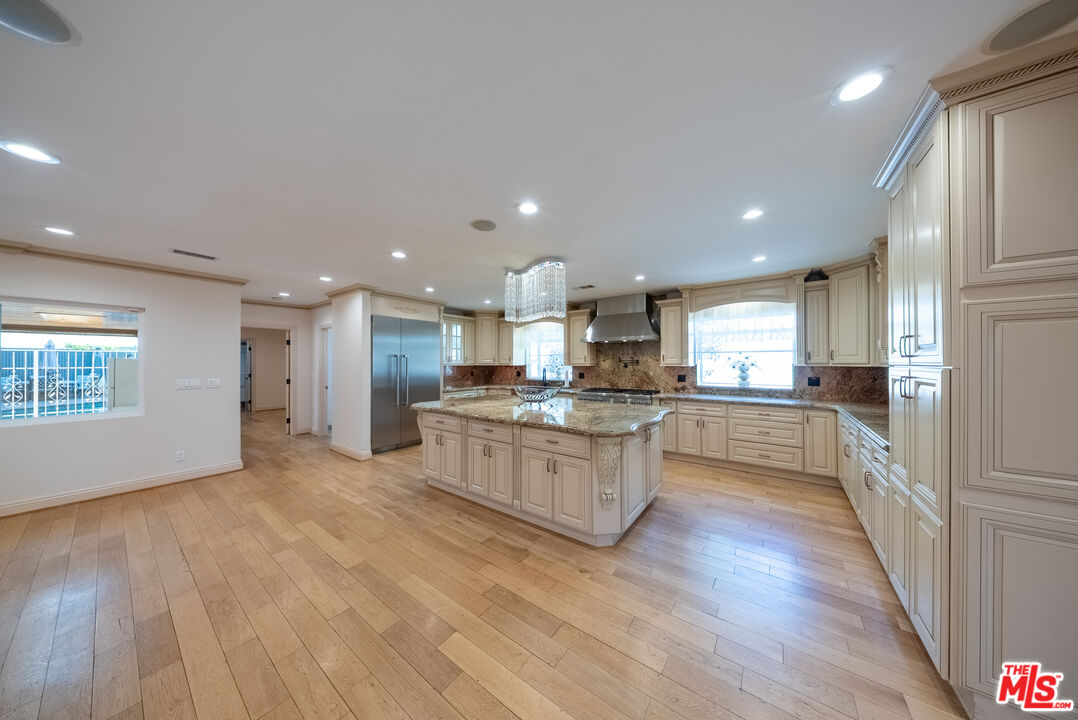 13847 Gilmore Street Van Nuys, CA 91401 - Photo 4 of 43 a large kitchen with kitchen island a sink dishwasher stove and white cabinets with wooden floor
