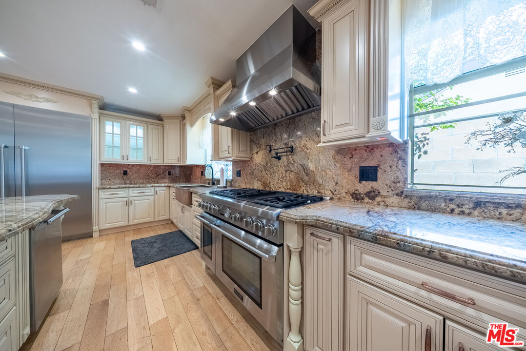 13847 Gilmore Street Van Nuys, CA 91401 - Photo 7 of 43 a kitchen with stainless steel appliances granite countertop a stove a sink and a refrigerator