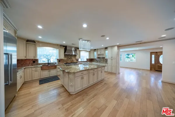 a kitchen with stainless steel appliances granite countertop a stove a refrigerator a sink wooden floor and a dining table with wooden floor