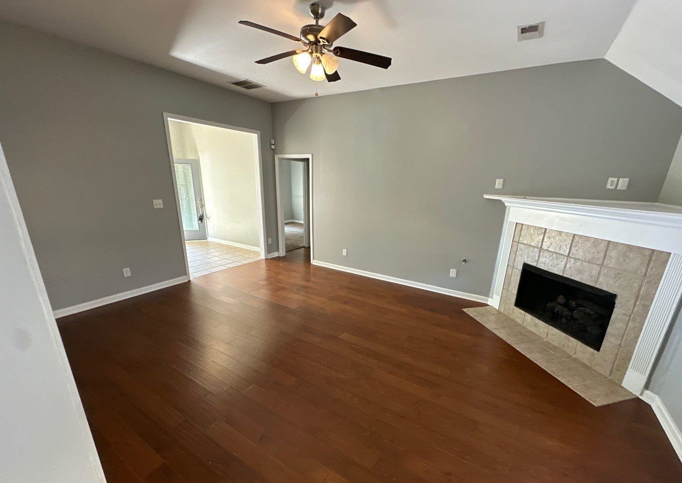 9420 Grove Road Cordova, TN 38016 - Photo 2 of 15 Unfurnished living room featuring dark wood-style flooring, a ceiling fan, a tile fireplace, and lofted ceiling