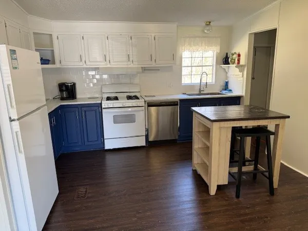 a kitchen with a refrigerator stove and wooden floor
