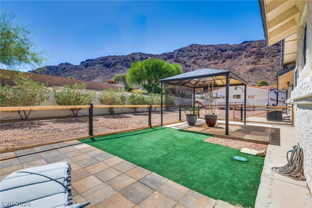 524 Swallow Cove Boulder City, NV 89005 - Photo 42 of 58 A private outdoor space with mountain views features a paved patio, covered seating, and a section of artificial turf.
