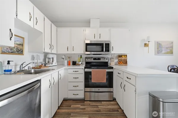 a kitchen with granite countertop a sink stainless steel appliances and white cabinets