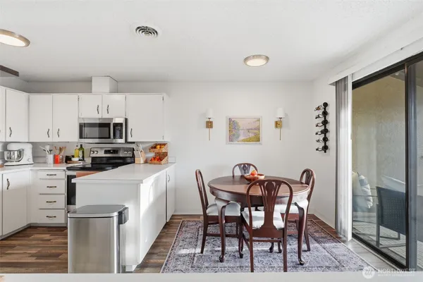 a kitchen with stainless steel appliances granite countertop a dining table chairs refrigerator and microwave