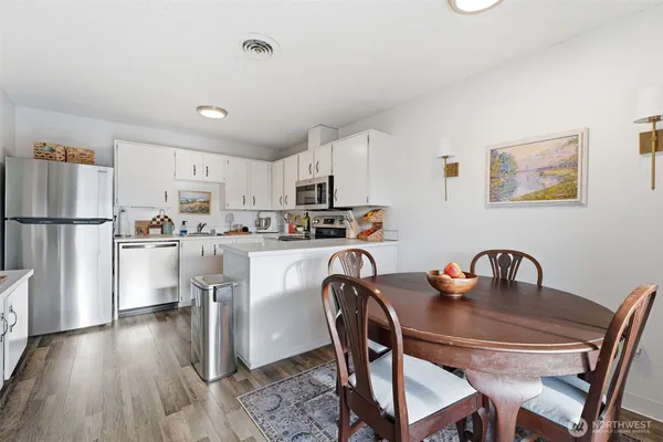 a kitchen with stainless steel appliances granite countertop a dining table chairs refrigerator and cabinets