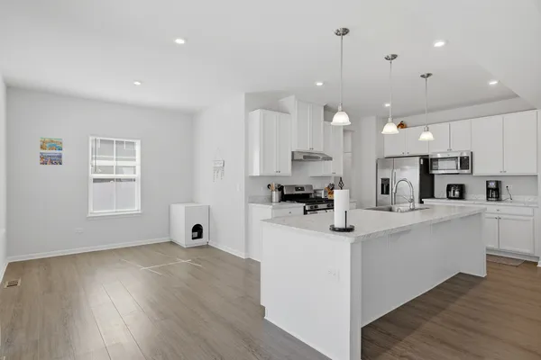 a kitchen with stainless steel appliances kitchen island granite countertop a sink cabinets and wooden floor