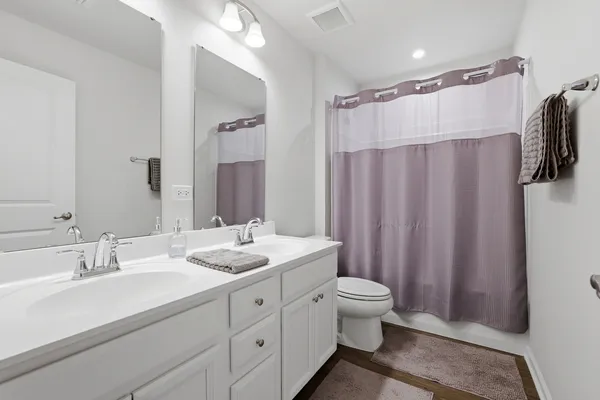 a bathroom with a double vanity sink toilet and shower