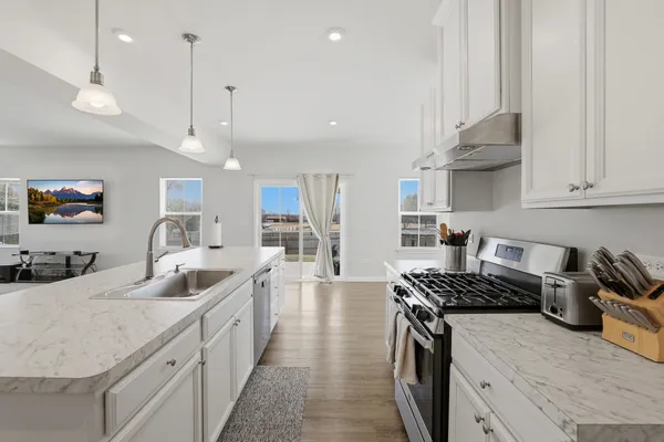a kitchen with stainless steel appliances granite countertop a sink a stove and a wooden floors