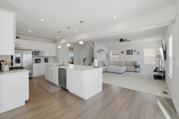 a large white living room with stainless steel appliances kitchen island lots of white furniture a rug a fireplace and a view of living room