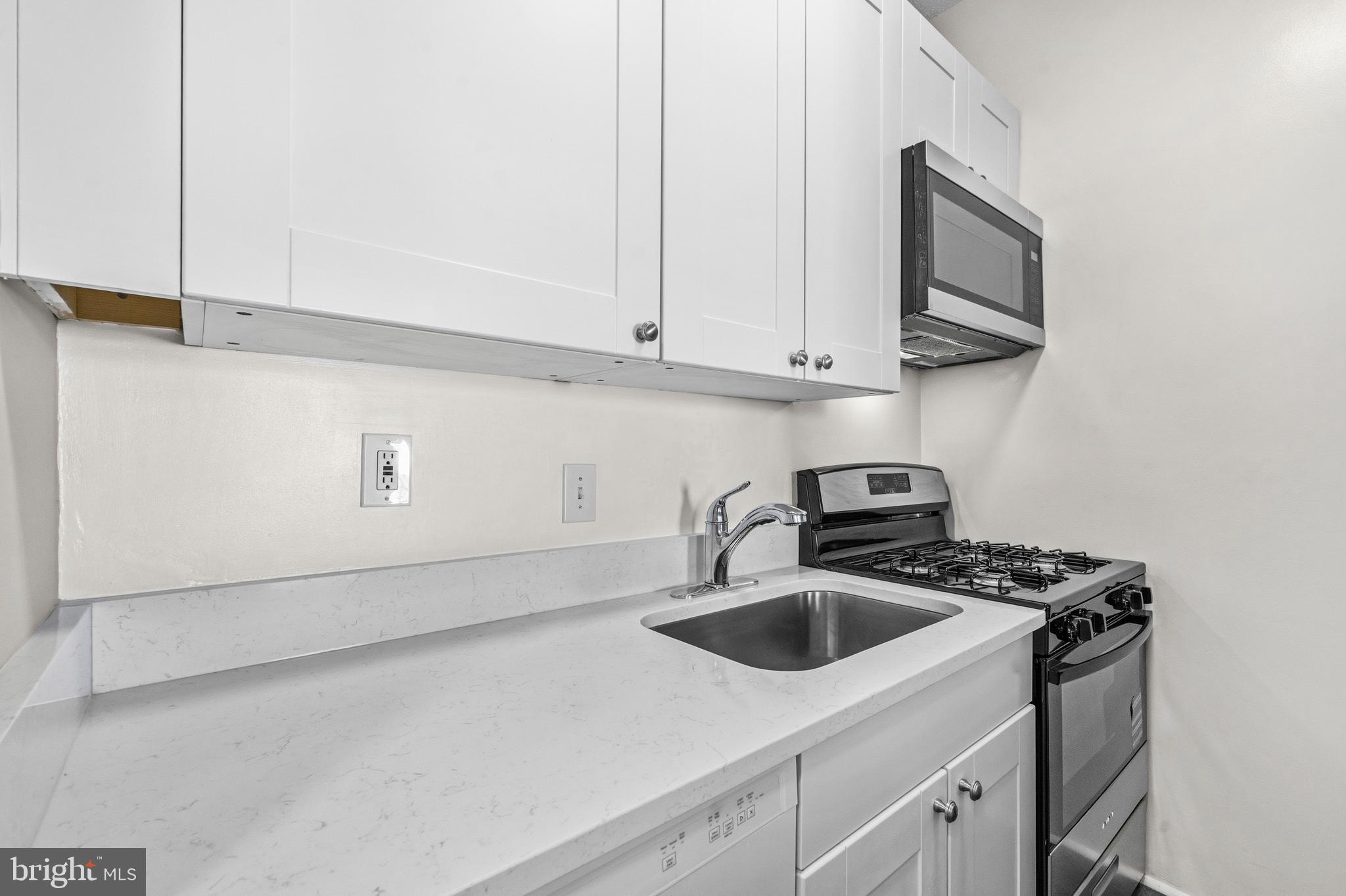 1851 Columbia Road Northwest, Unit 401 Washington, DC 20009 - Photo 9 of 27 a kitchen with stainless steel appliances granite countertop a sink a stove and a microwave