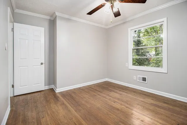 a view of an empty room with wooden floor and a window