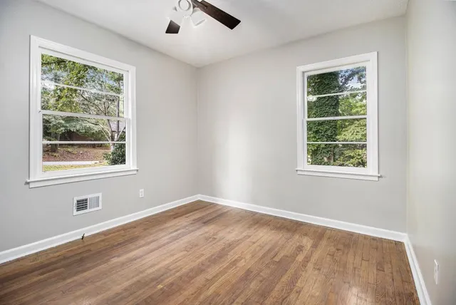 a view of an empty room with wooden floor and a window