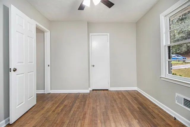 a view of empty room with wooden floor and fan