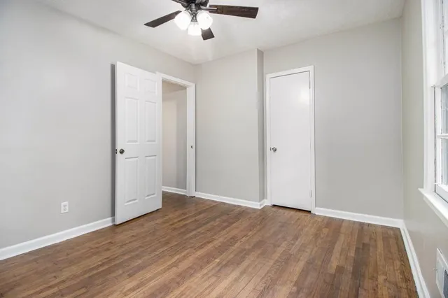 an empty room with wooden floor and windows