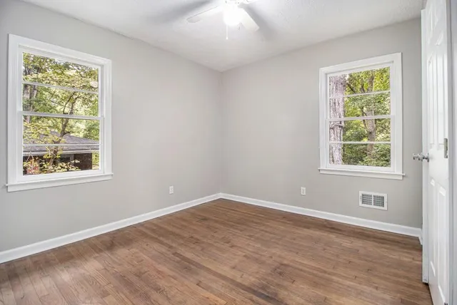 a view of an empty room with wooden floor and a window