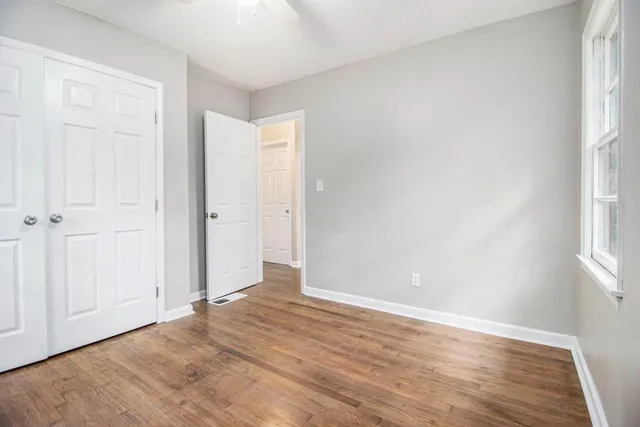 an empty room with wooden floor and windows