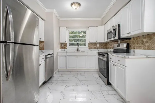 a kitchen with white cabinets stainless steel appliances and a sink