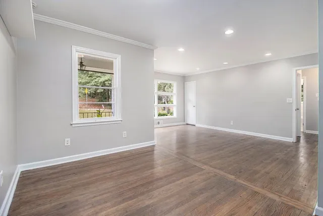 a view of an empty room with wooden floor and a window