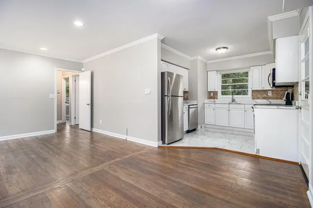 a view of a kitchen with refrigerator and wooden floor