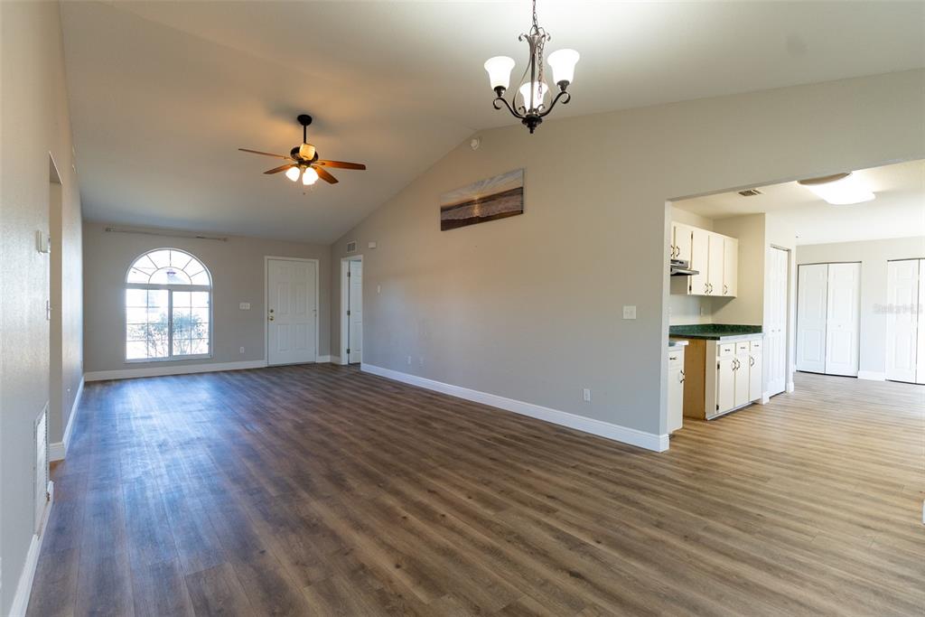15651 Southwest 19th Terrace Ocala, FL 34473 - Photo 13 of 68 a view of empty room with wooden floor and kitchen view