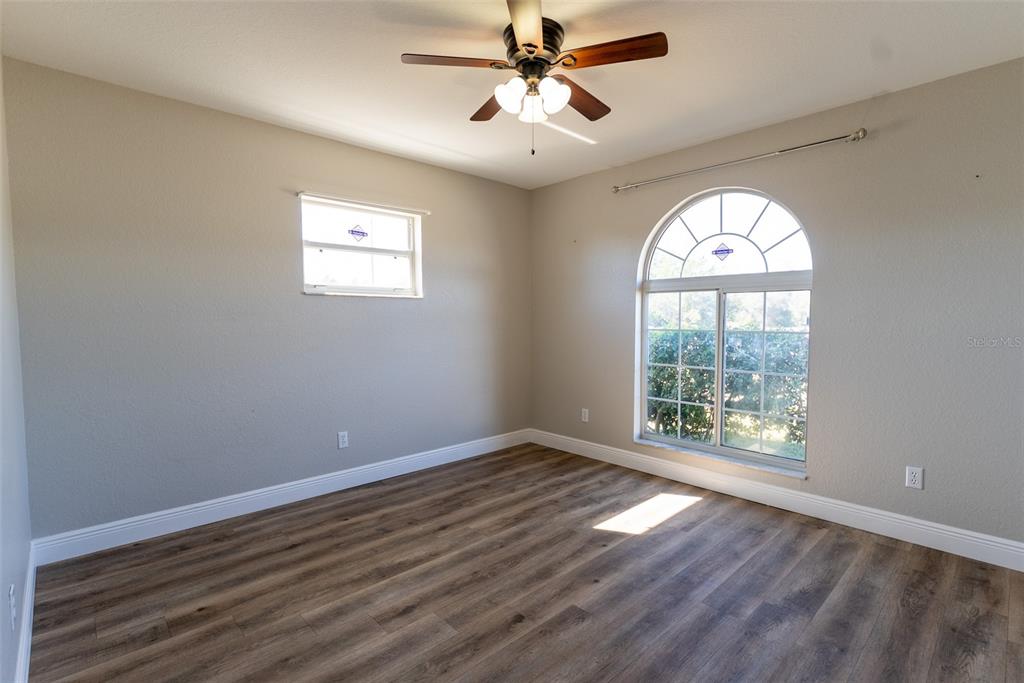15651 Southwest 19th Terrace Ocala, FL 34473 - Photo 45 of 68 an empty room with wooden floor fan and windows