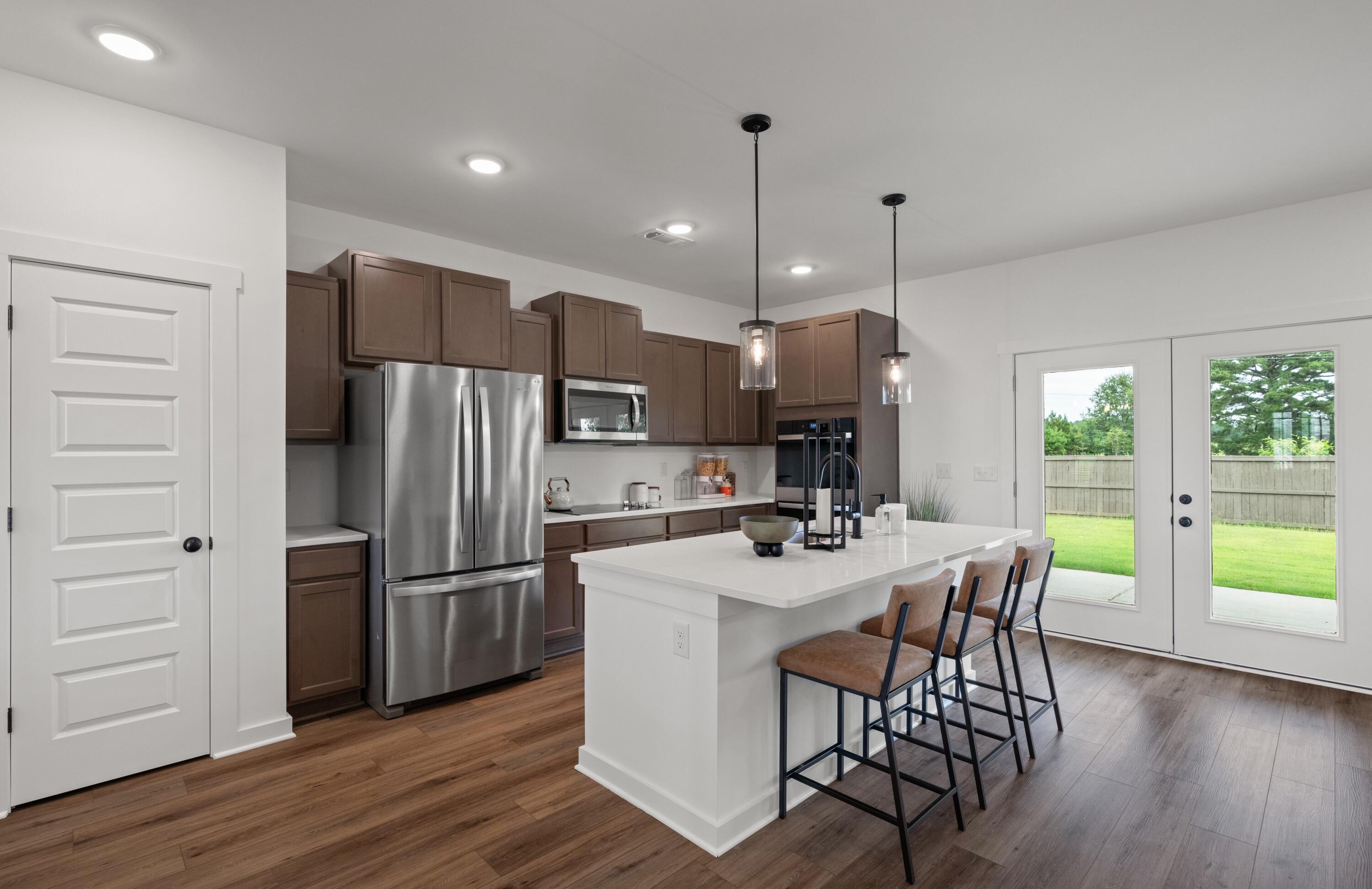 Lot 10 Clarke Hill Road Freeport, FL 32439 - Photo 6 of 52 a kitchen with kitchen island a refrigerator a stove a dining table and chairs with wooden floor