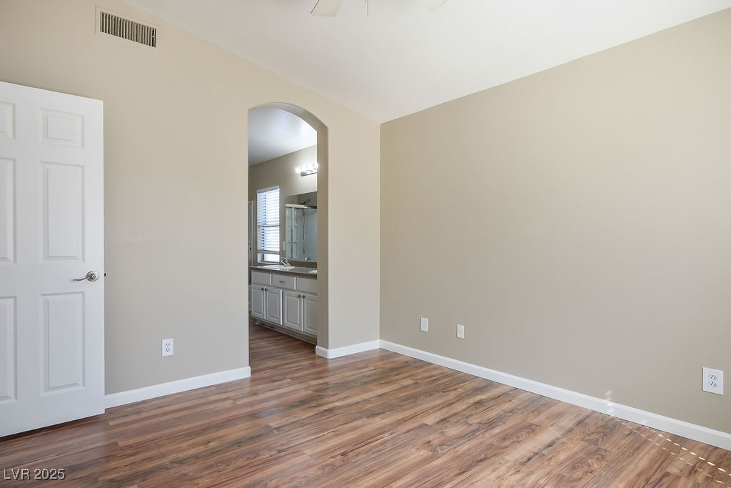 6610 Tumbleweed Ridge Lane, Unit 101 Henderson, NV 89011 - Photo 19 of 24 Empty room featuring arched walkways, dark wood-style flooring, and ceiling fan