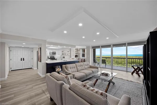 a living room with furniture floor to ceiling window and wooden floor