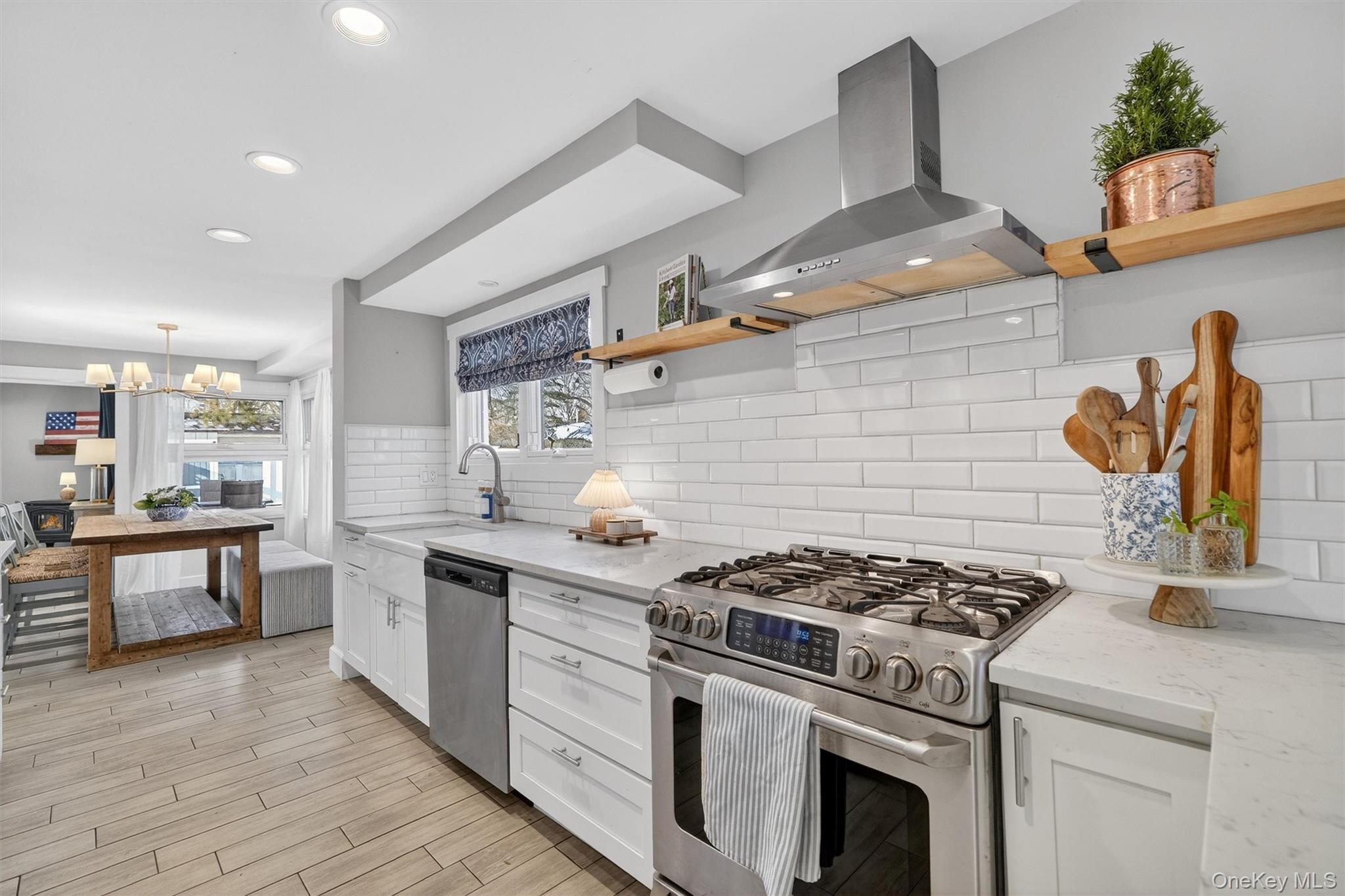 18 Lambert Lane New Rochelle, NY 10804 - Photo 13 of 47 Kitchen with open shelves, appliances with stainless steel finishes, wall chimney exhaust hood, white cabinets, and light stone countertops