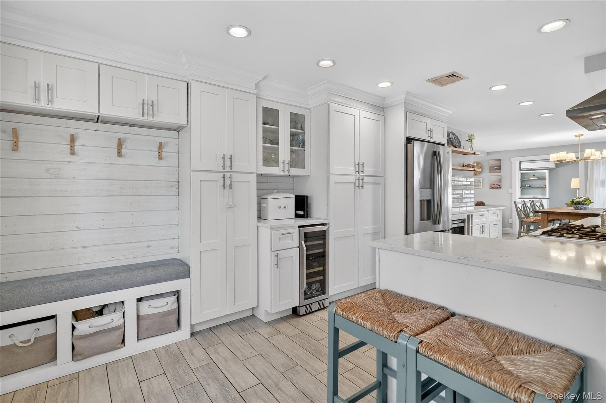 18 Lambert Lane New Rochelle, NY 10804 - Photo 16 of 47 Kitchen featuring light stone countertops, glass insert cabinets, white cabinetry, a breakfast bar area, and stainless steel appliances