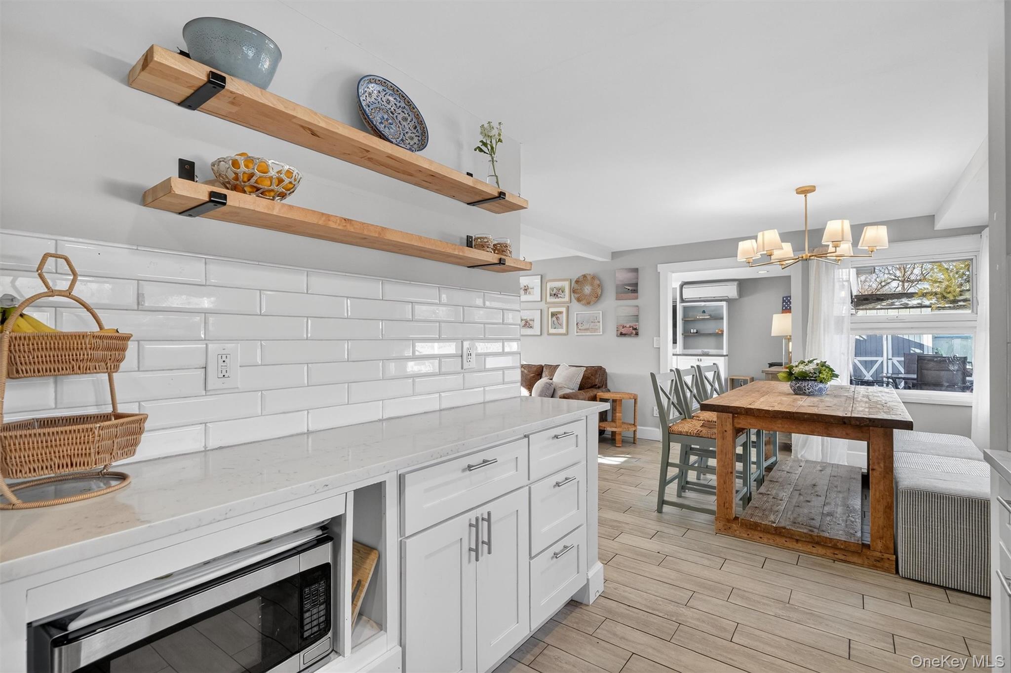 18 Lambert Lane New Rochelle, NY 10804 - Photo 18 of 47 Kitchen featuring light stone countertops, open shelves, stainless steel microwave, white cabinets, and wood tiled floors