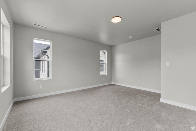 1567 North 3250 West Provo, UT 84601 - Photo 22 of 22 Neutral tone wall paint with white trim, light gray carpet flooring, multiple windows, and a flush mount ceiling light fixture