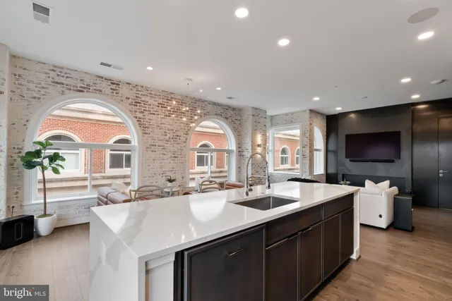 a large kitchen with stainless steel appliances a large counter top a stove a sink and a refrigerator